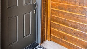 Una puerta de madera oscura con un picaporte de metal y un cartel de bienvenida con árboles y el año 2026.