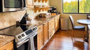 Una cocina con armarios de madera, microondas, estufa y comedor con mesa y sillas.