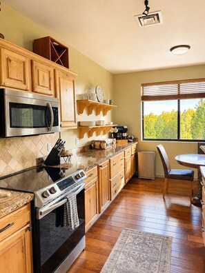 A kitchen with wooden cabinets, a microwave, a stove, and a dining area with a table and chairs.