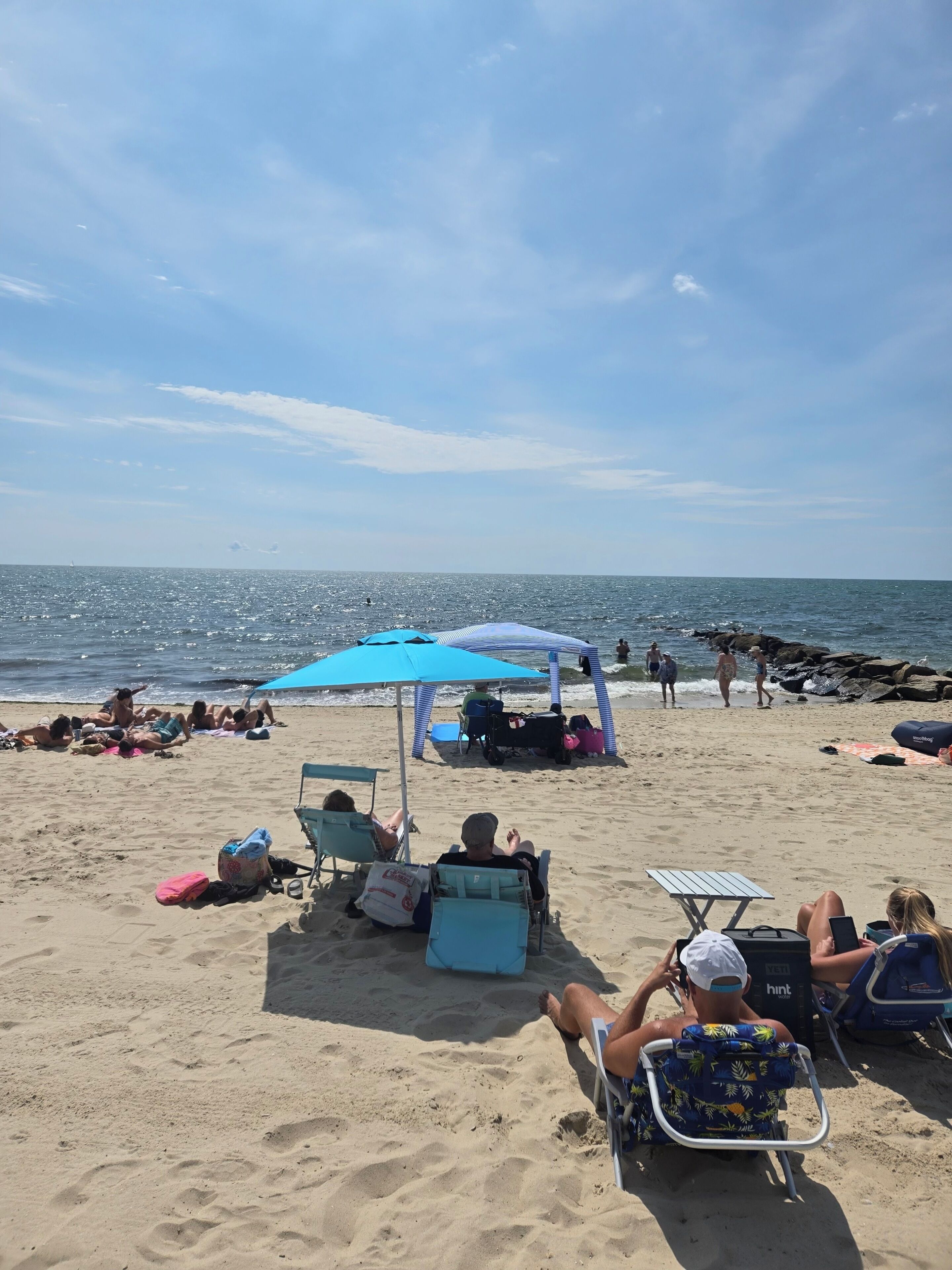 Una playa con gente tomando el sol y relajándose bajo sombrillas.