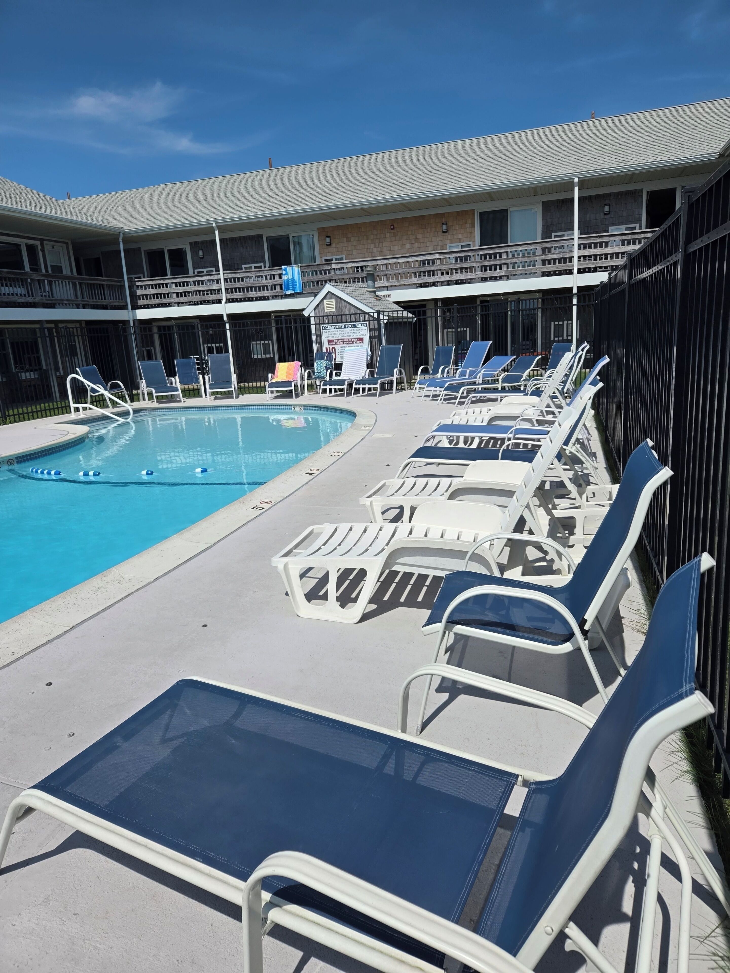 Zona de piscina con sillones de descanso y un cartel que indica una habitación en venta.