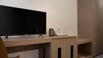 A modern hotel room with a flat-screen TV, wooden desk, and built-in wardrobe.