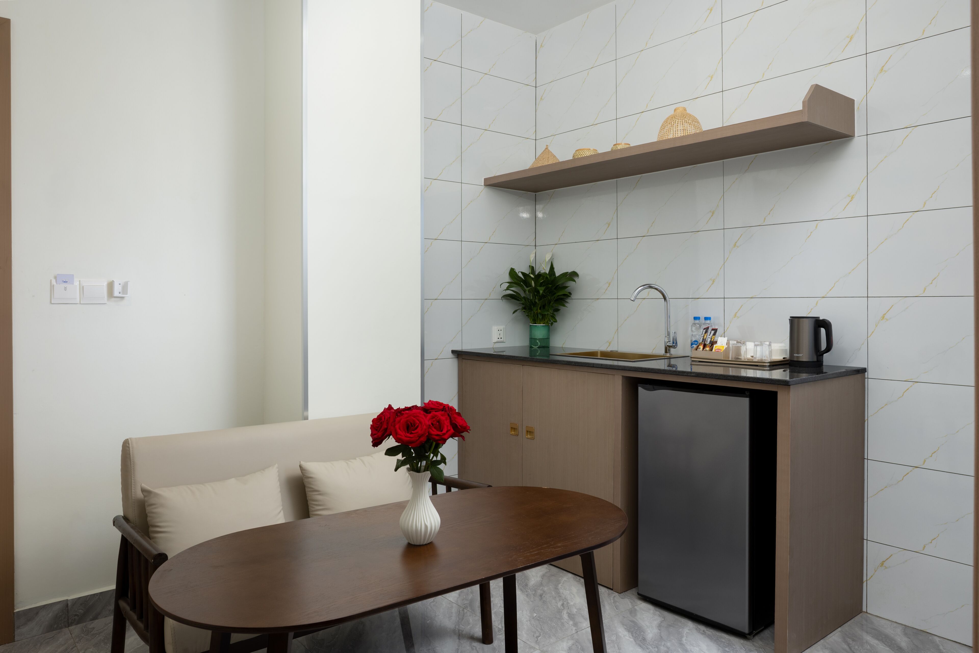 A compact kitchenette with a built-in refrigerator, a small countertop, and a shelf above the sink.