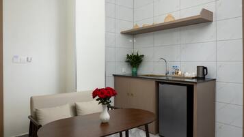 A compact kitchenette with a built-in refrigerator, a small countertop, and a shelf above the sink.