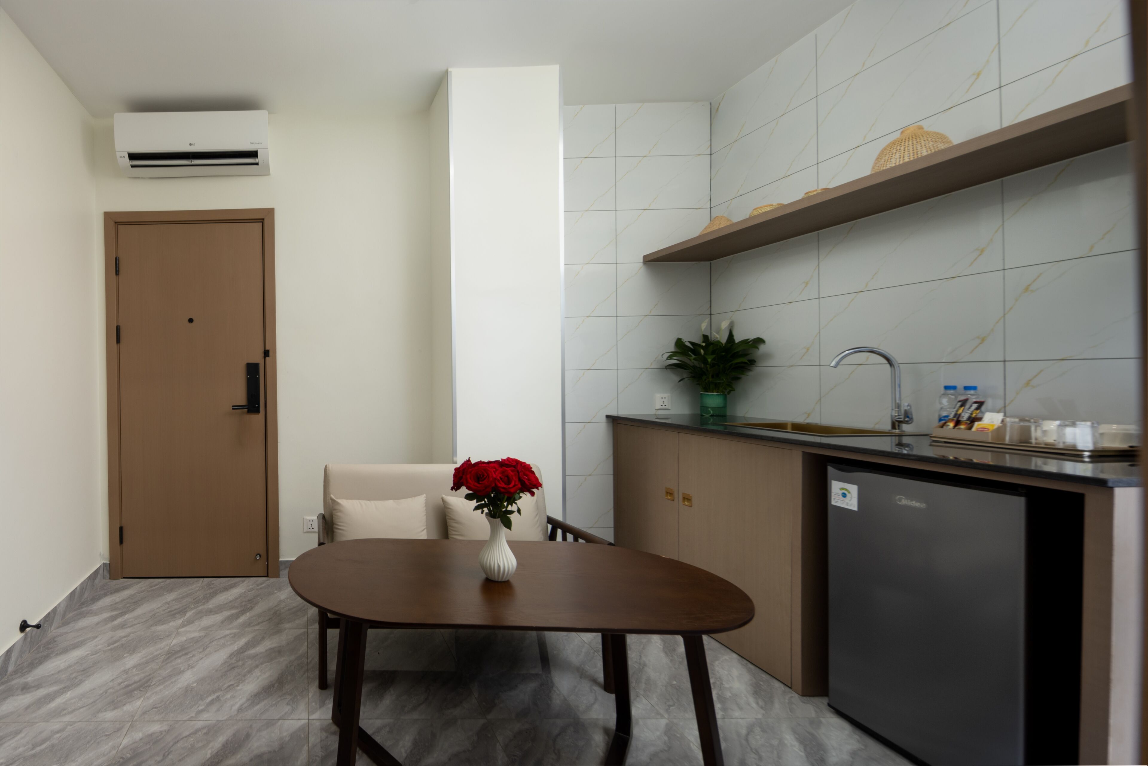 Cocina compacta con comedor, horno empotrado, lavamanos y un refrigerador pequeño.