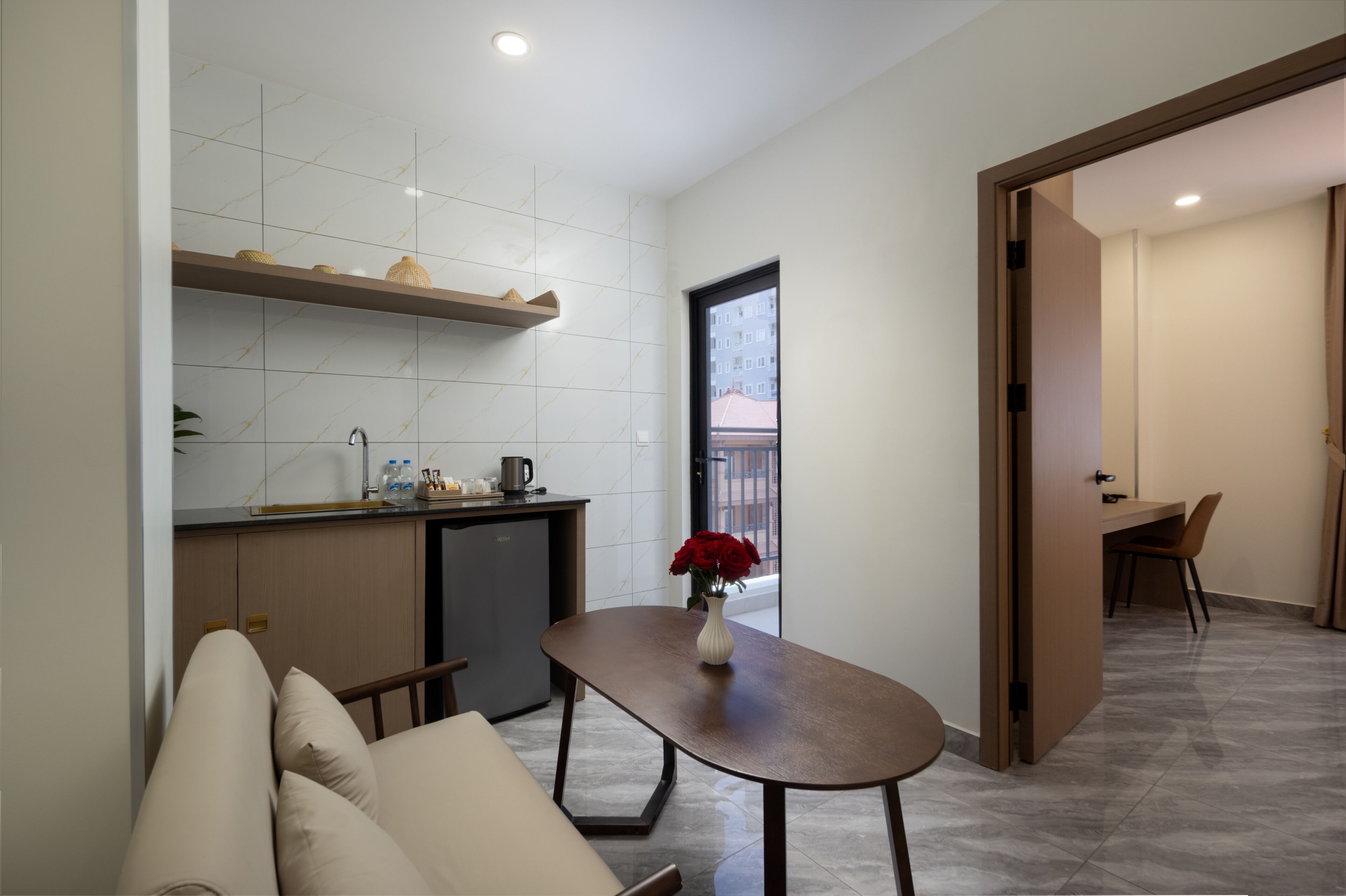 Una cocina moderna con horno empotrado, un comedor con mesa y sillas, y vista a un edificio.