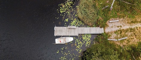 A wooden dock extending into a body of water with a small boat moored at the end.
