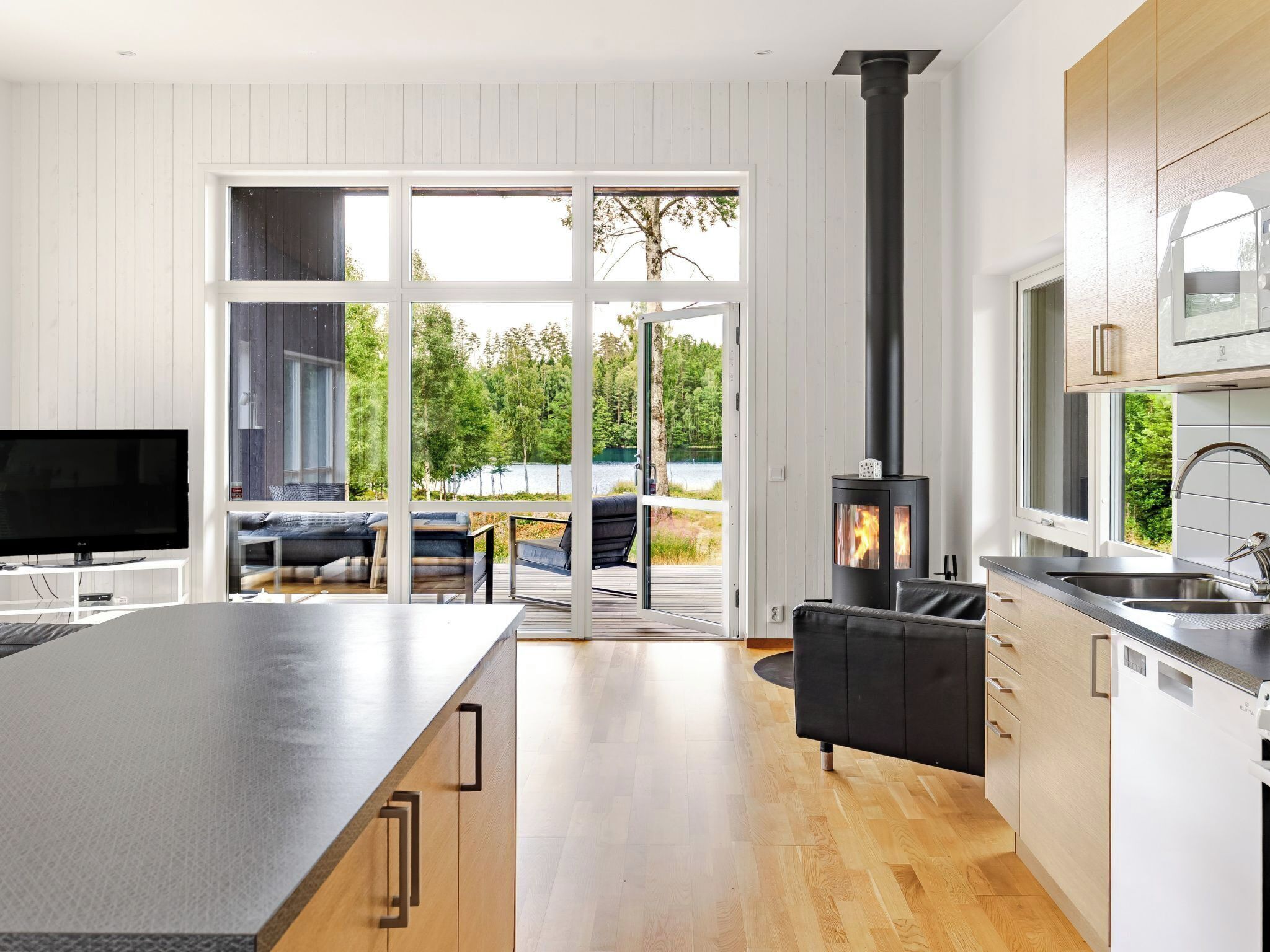 Ett modernt kök med en central köksö, en inbyggd spis och en stor skjutdörr i glas som leder ut till en uteplats.