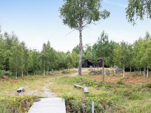 A wooden pathway leading to a modern building surrounded by a forest. - Paradiset 2 by Interhome (Holmsjö)