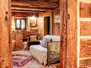 Une pièce chaleureuse dans un chalet en rondins, avec un lit, une chaise, un bureau et une fenêtre.