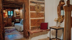 A rustic room with a wooden bench, a mirror, and a small table with a vase.