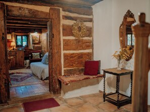 A rustic room with a wooden bench, a mirror, and a small table with a vase.