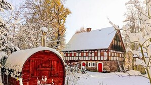 A traditional half-timbered house with a red barn in a snowy setting.