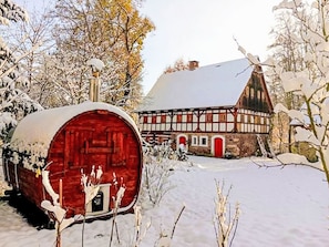 A traditional half-timbered house with a red barn in a snowy setting.