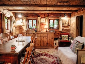 Un intérieur rustique en bois, avec une table à manger, des chaises, un canapé et un coin cuisine.
