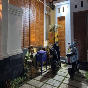 Un patio con una scooter, una silla azul y un armario de madera.