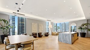 Een ruime, moderne keuken met een marmeren kookeiland, grote ramen en een hoog plafond met inbouwverlichting.
