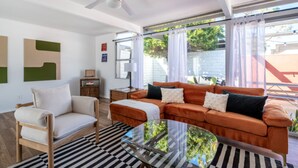 Ein Wohnzimmer mit einer Couch, einem Sessel und einem Glastisch.