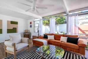 A living room with a sofa, armchair, and a glass coffee table. - California Sunshine at Casa Louise (Palm Springs)