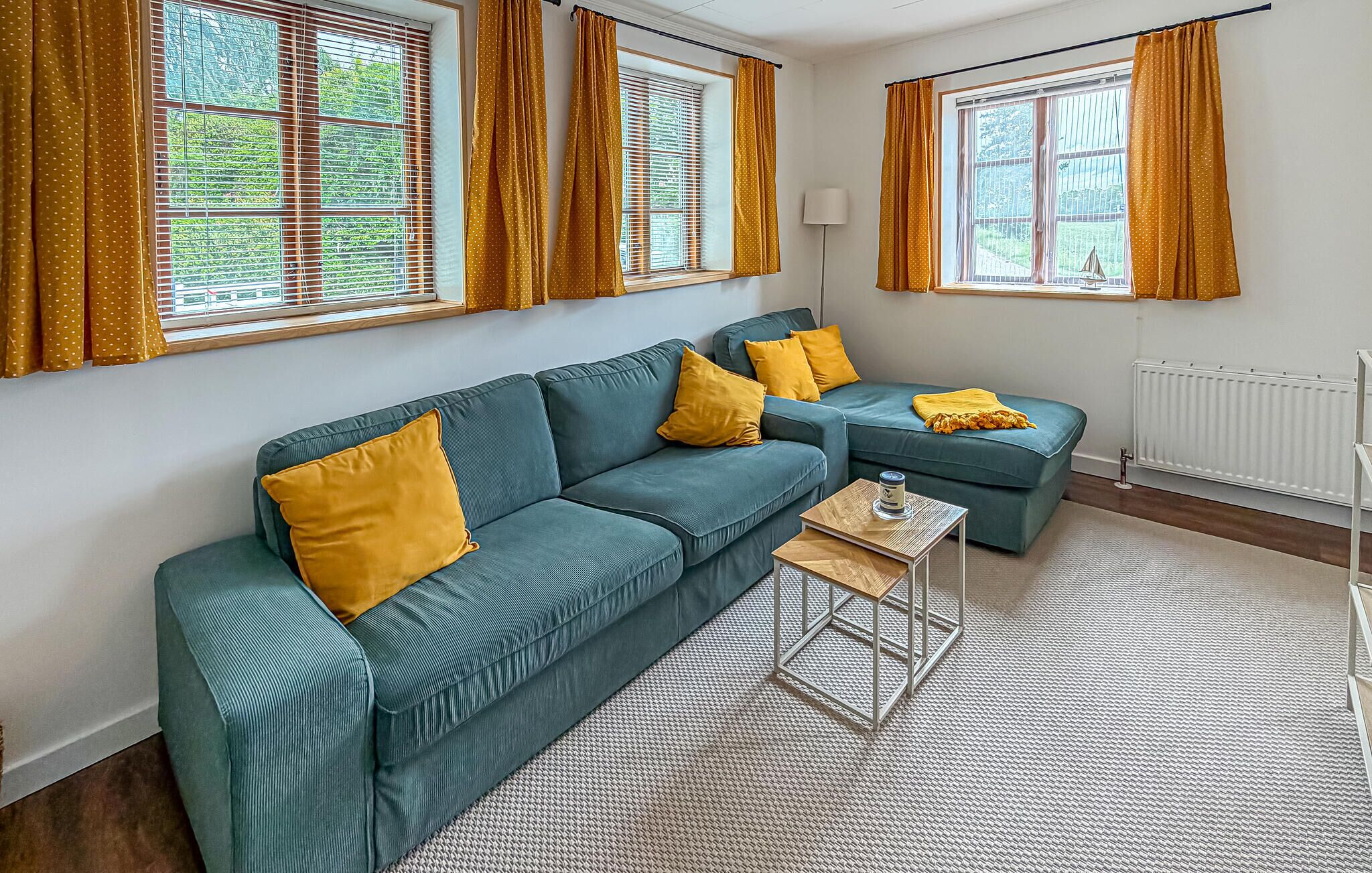 Una sala de estar con un sofá modular, una mesita y una ventana con cortinas.