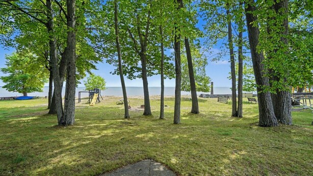 A park with trees, a playground, and a view of the water. - Granny`s Cabin on Sandy Lake Huron (Au Gres)