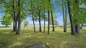 Un parc avec des arbres, une aire de jeux et une vue sur l’eau.