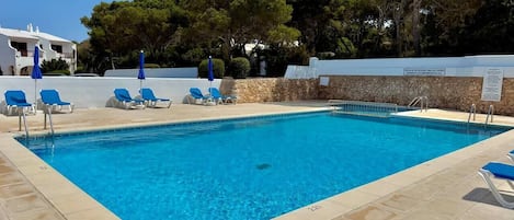 A rectangular swimming pool with clear blue water, surrounded by beige tiles.