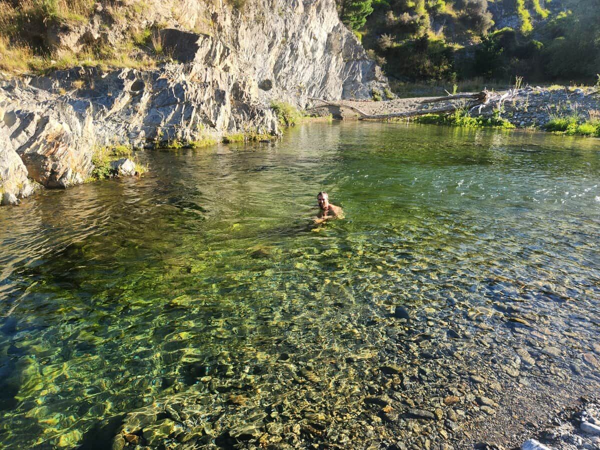 Ein natürlicher Gewässer mit klarem Wasser, umgeben von felsigem Gelände und Vegetation.