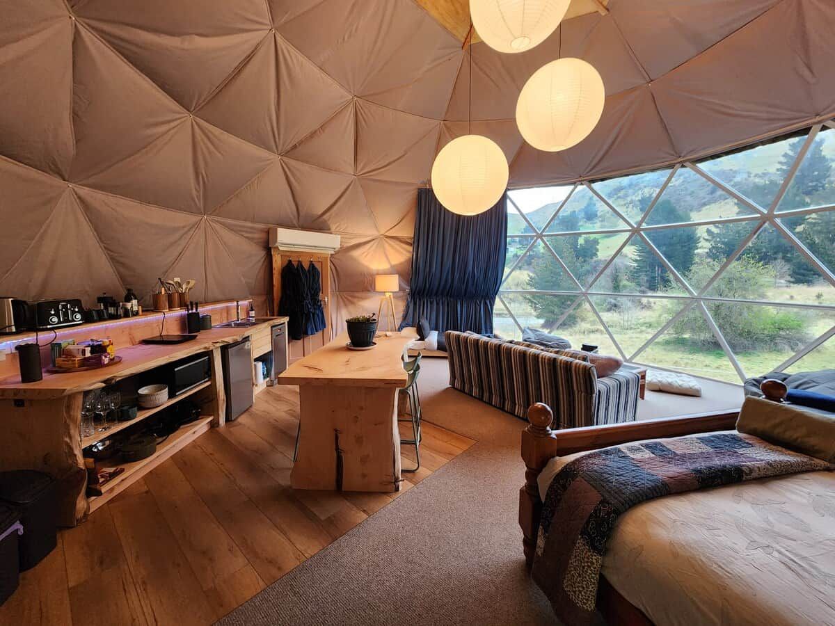 Eine gemütliche Zelteinrichtung mit einer zentralen Essecke, einem Bett und Blick ins Freie.