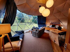 A cozy interior of a geodesic dome tent with a sofa, a small table, and a bar area.