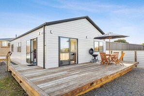 Una casa móvil de un nivel con terraza, una parrilla y asientos exteriores.