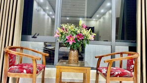 A room with a glass table, two wooden chairs, and a vase with flowers. - Dong Thanh Hotel (Vo Cuong)