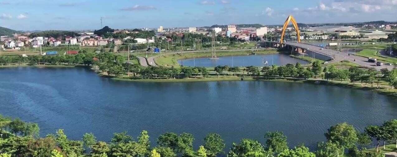 A river with a bridge, a park, and buildings in the background.