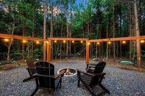 An outdoor seating area with a fire pit, surrounded by wooden chairs and a hammock. - Secluded, Hot Tub, Games, Luxury, Fire pit, Pets (Broken Bow)