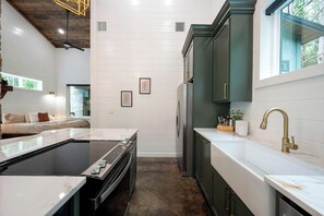 A modern kitchen with a built-in stove, a large island, and a sink with a gold faucet. - Secluded, Hot Tub, Games, Luxury, Fire pit, Pets (Broken Bow)