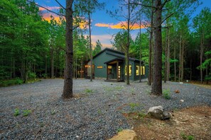 A cabin surrounded by trees with a gravel driveway. - Secluded, Hot Tub, Games, Luxury, Fire pit, Pets (Broken Bow)