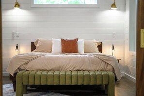 A neatly made bed with a green upholstered bench in front, two bedside lamps, and a window above. - Secluded, Hot Tub, Games, Luxury, Fire pit, Pets (Broken Bow)
