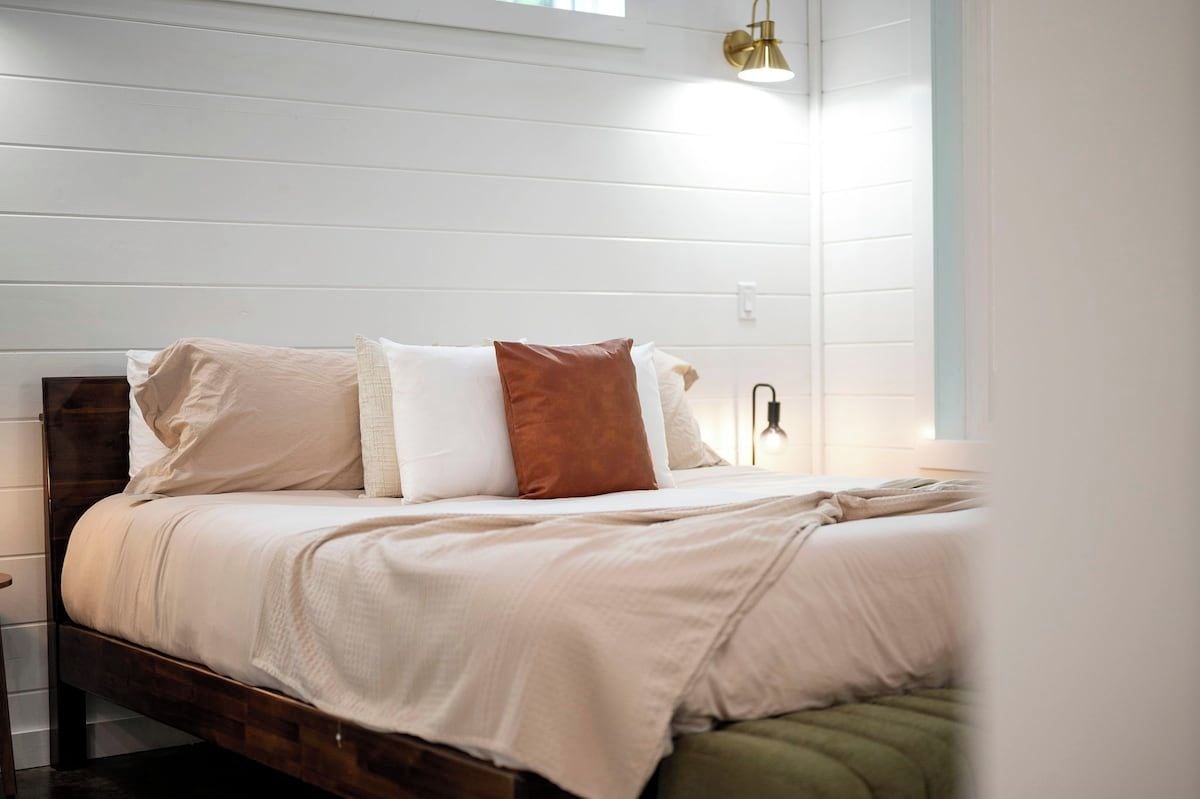 A bed with a wooden headboard, white bedding, and a brown pillow.