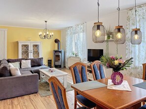 Ein Wohnzimmer mit einer Couch, einem Esstisch, Stühlen, einem Fernseher und einem Kamin.