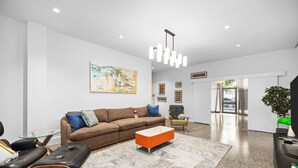 Een moderne woonkamer met een bruine bank, een glazen salontafel en een zwarte leren fauteuil.