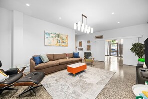 Ein modernes Wohnzimmer mit einem braunen Sofa, einem Glastisch und einem schwarzen Ledersessel.