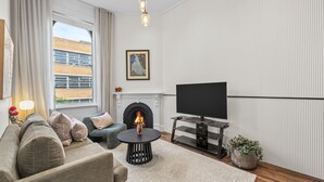 Een moderne woonkamer met een open haard, een zithoek, een televisie en een potplant.