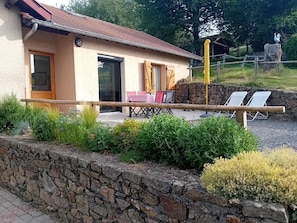 Et hus med en stenvæg, en træterrasse og et rustikt hegn.