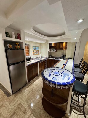 A modern kitchen with a central island, wooden cabinets, and a herringbone floor pattern. - Velas Vallarta Beach Front Resort (Puerto Vallarta)