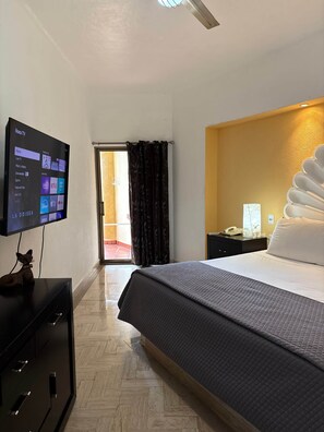 A hotel room with a bed, a TV displaying streaming services, a desk with a phone, and a view of the outside. - Velas Vallarta Beach Front Resort (Puerto Vallarta)