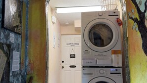 A laundry room with two stacked washers and dryers, a door labeled 'GRANNY'S CORNER SUITE,' and a wall mural. - Granny’s Corner Suite - 2 bed home near Medora, Theodore Roosevelt National Park (Dickinson)