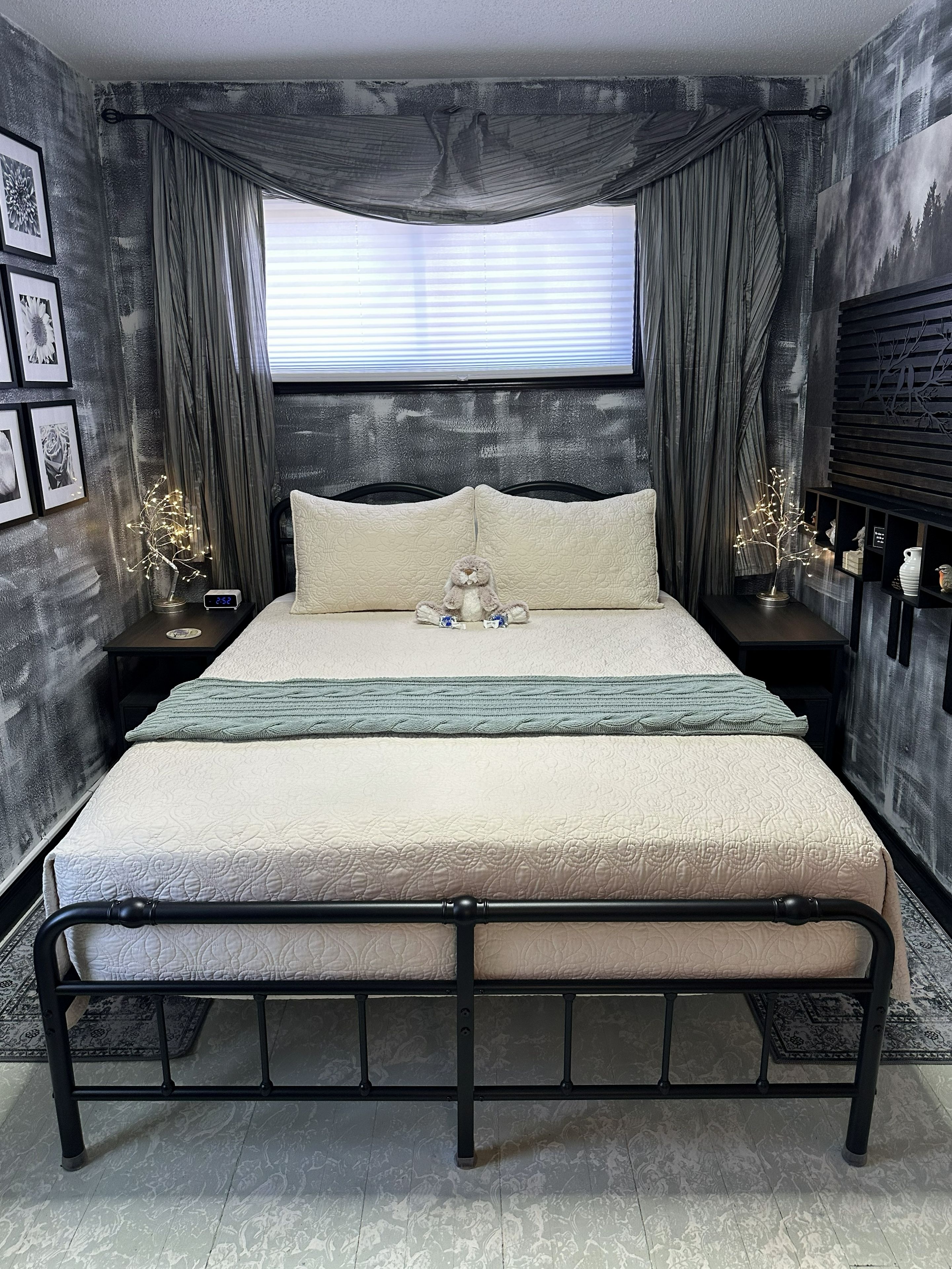A bed with a headboard, a bedside table with a clock, and a wall-mounted shelf with decorative items.