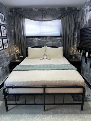 A bed with a headboard, a bedside table with a clock, and a wall-mounted shelf with decorative items.