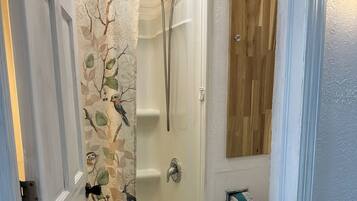 A bathroom with a shower, toilet, and a wooden wall.