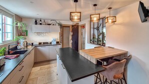 A modern kitchen with a central island, bar stools, and pendant lighting. - Belle maison rénovée (Dax)